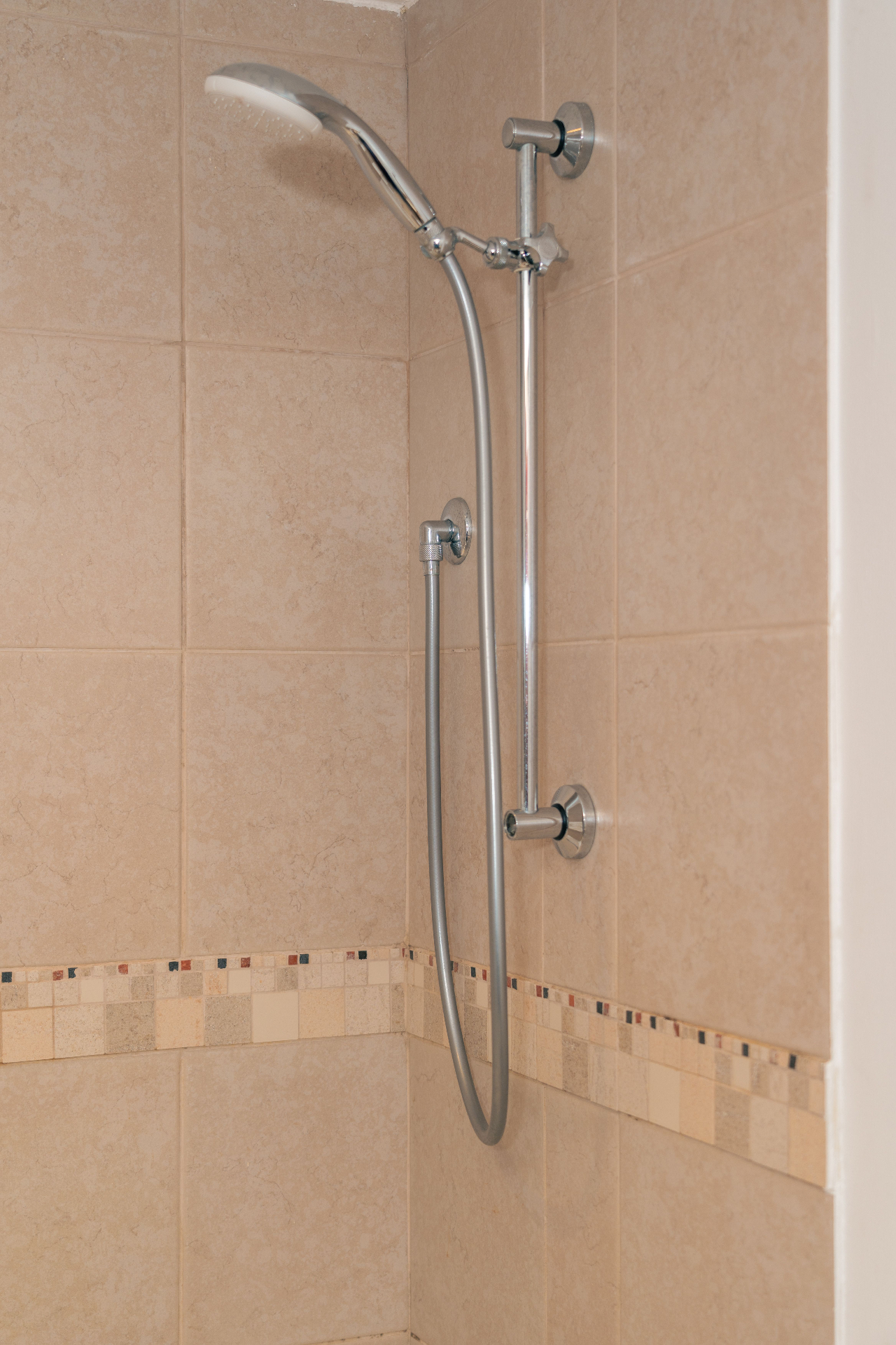 Chrome shower rail fitted against warm neutral bathroom tiles